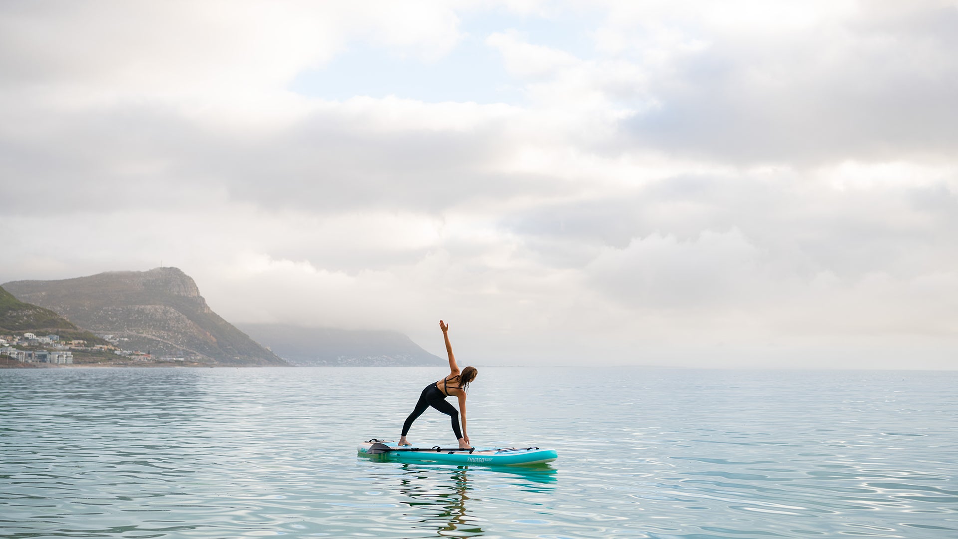 Ein schwimmendes Yoga-Board, das eine Mischung aus Balance, Kraft und Gelassenheit auf der weiten Leinwand ruhiger Gewässer einlädt.