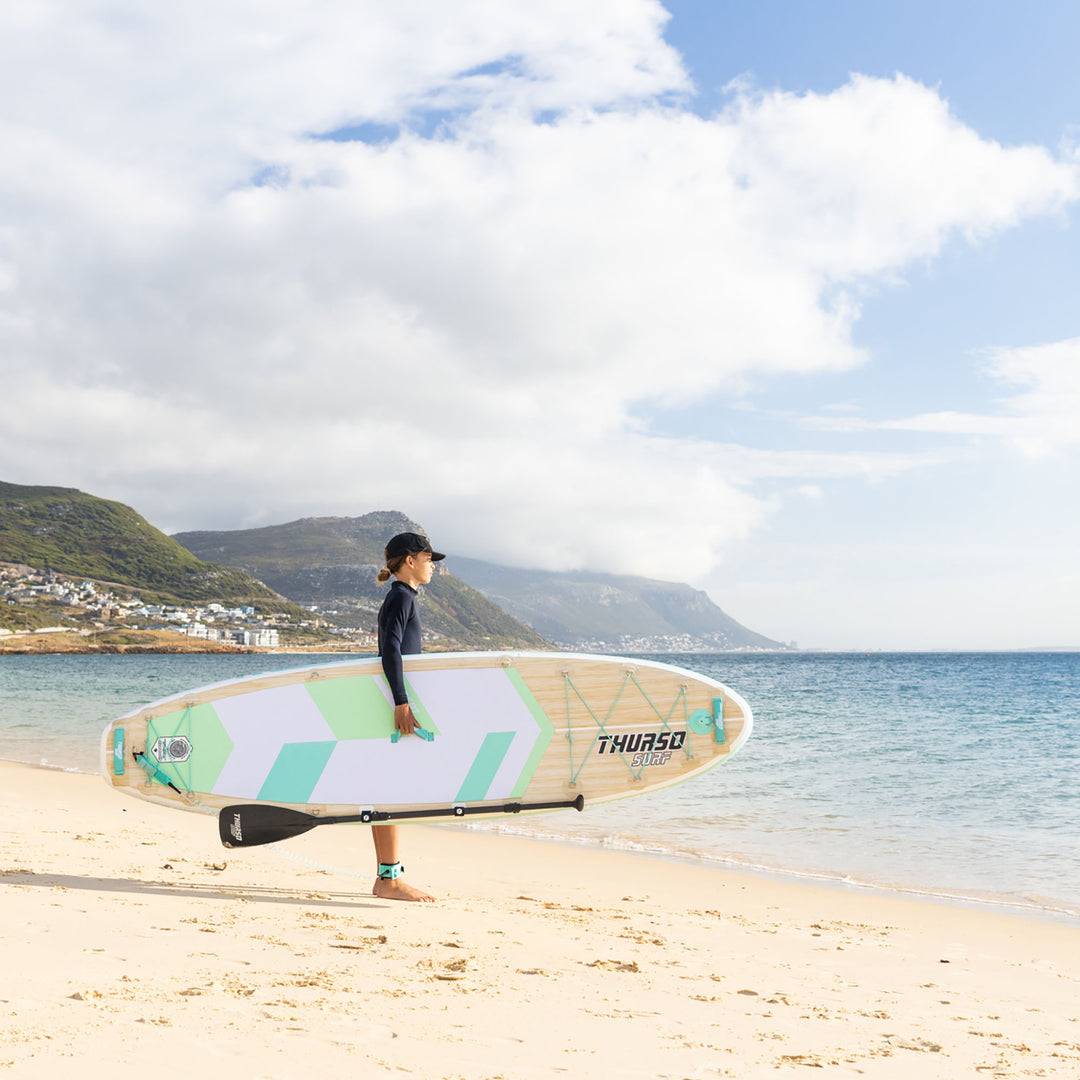 boy carrying a sup standing at the beach
