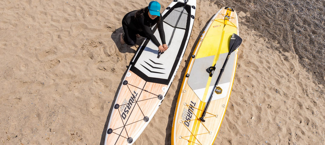 Woman leaning over two Thurso Surf inflatable stand up paddleboards