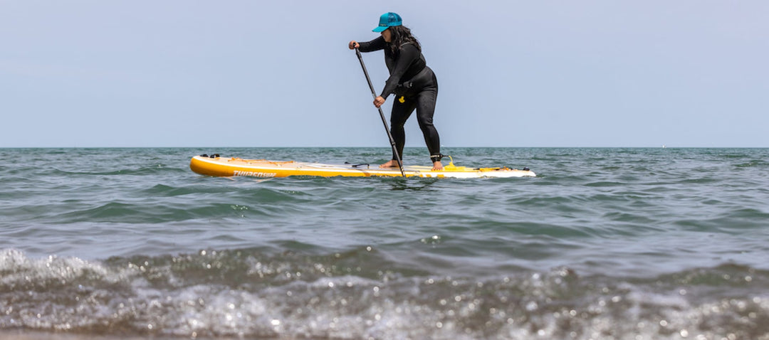 Woman paddling a SUP board through choppy water