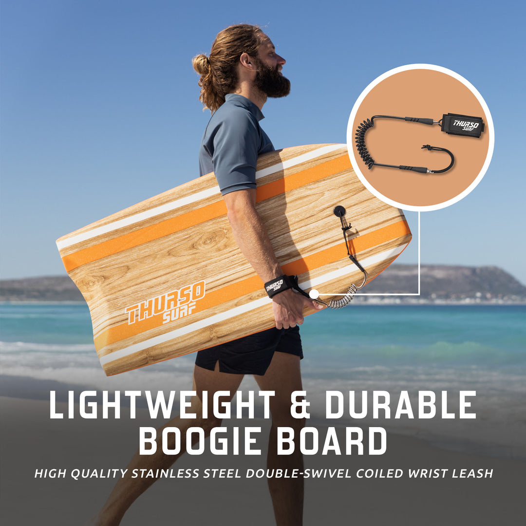 A man walking on a tropical beach carrying a Tangerine orange wood-grain Thurso Surf Quill bodyboard under his arm, ready for surfing
